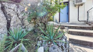 A stone wall with plants, a blue door, and a staircase leading to a building. - Amazing home in Asté with WiFi (Asté)