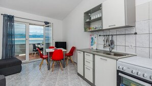 A modern kitchen with a dining area, a large window with a view, and a built-in oven. - Apartments Palaic (Vir)