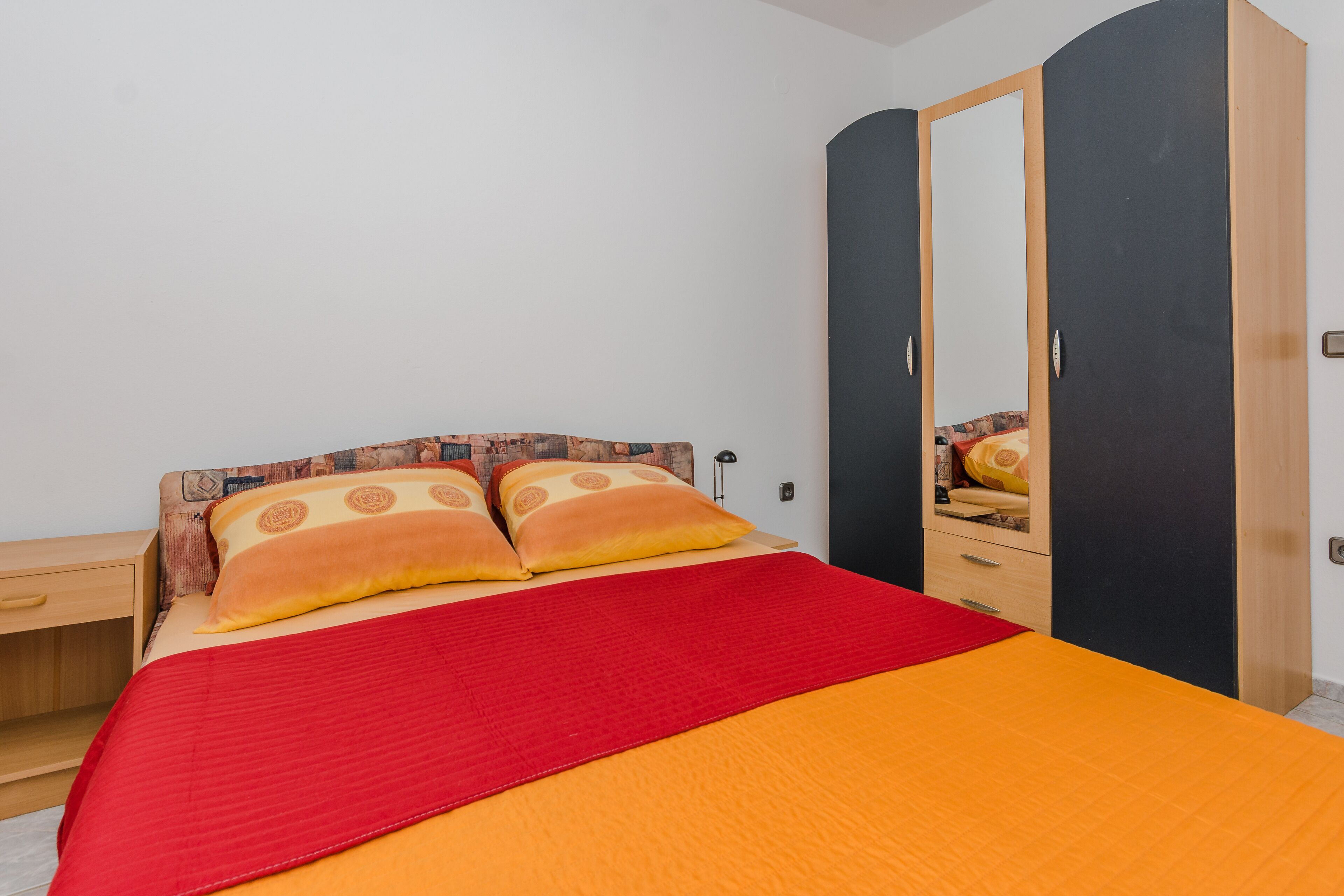 Un dormitorio con cama, armario y mesita de noche.