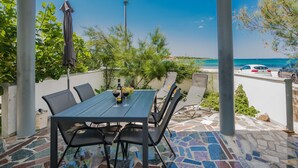 An outdoor patio with a table and chairs, a bottle of wine, and a view of the sea. - Apartments Palaic (Vir)