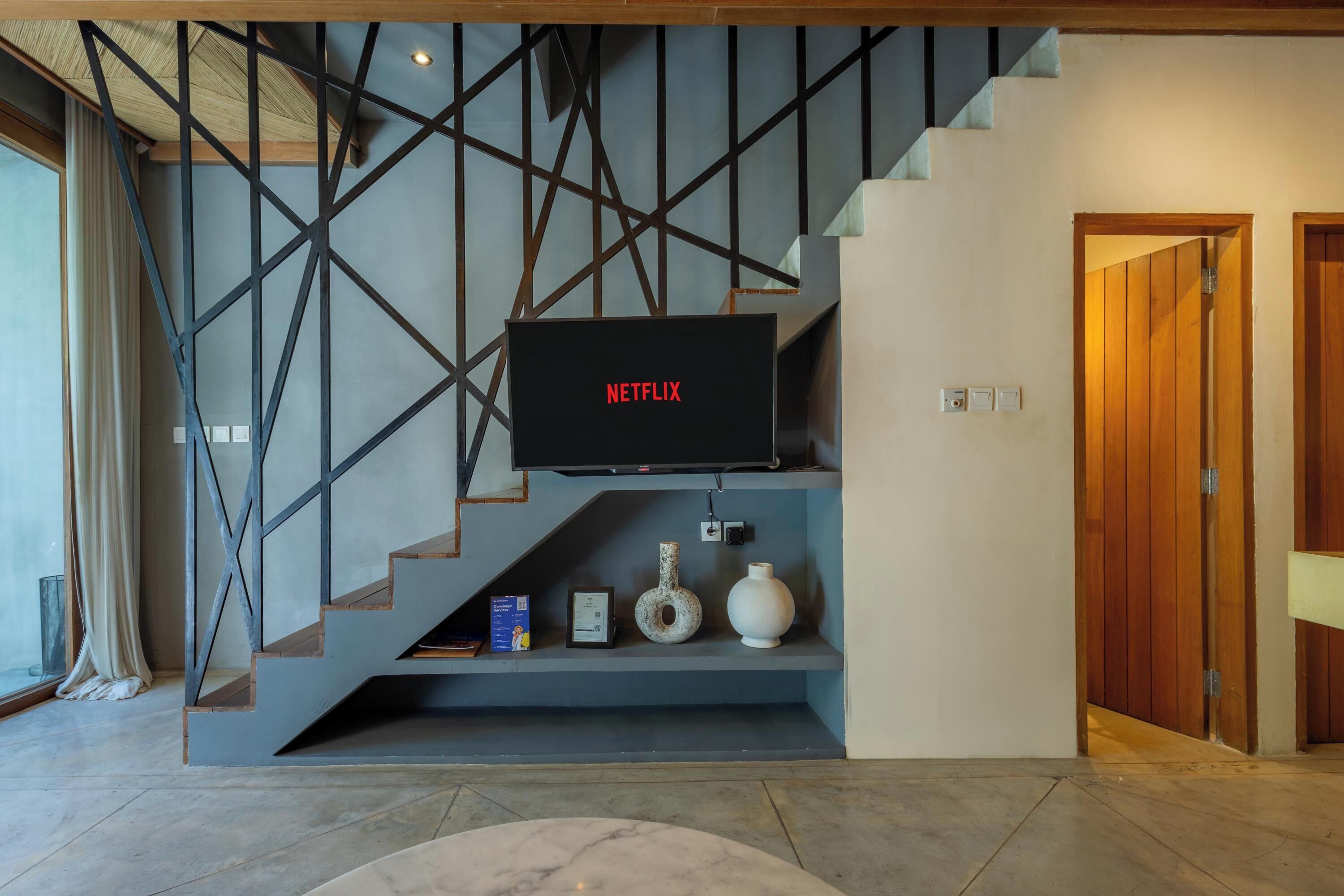 A modern interior with a staircase, a mounted television, and a wooden door.
