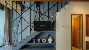 Un interior moderno con una escalera, un televisor montado y una puerta de madera.