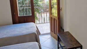 A room with two beds, a wooden bench, and a view of a balcony with plants. - 🌞 ENJOY CASA MATTARELLA 🌞 San Vito lo Capo (San Vito Lo Capo)