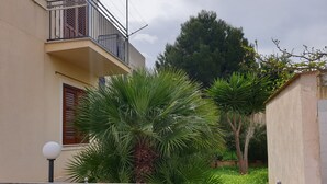 A residential building with a balcony, a small garden with palm trees, and a metal fence. - 🌞 ENJOY CASA MATTARELLA 🌞 San Vito lo Capo (San Vito Lo Capo)