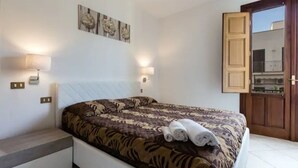 A bedroom with a bed, two wall-mounted lamps, a door, and a small bench. - 🌞 ENJOY CASA MATTARELLA 🌞 San Vito lo Capo (San Vito Lo Capo)