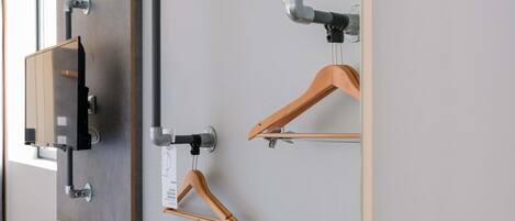 A wall-mounted TV, two wooden hangers, and a shelf.