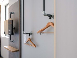 Una habitación moderna con televisor integrado, perchero de madera y una estantería.