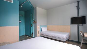 A hotel room with a large bed, a smaller bed, a TV mounted on the wall, and a wooden chair.