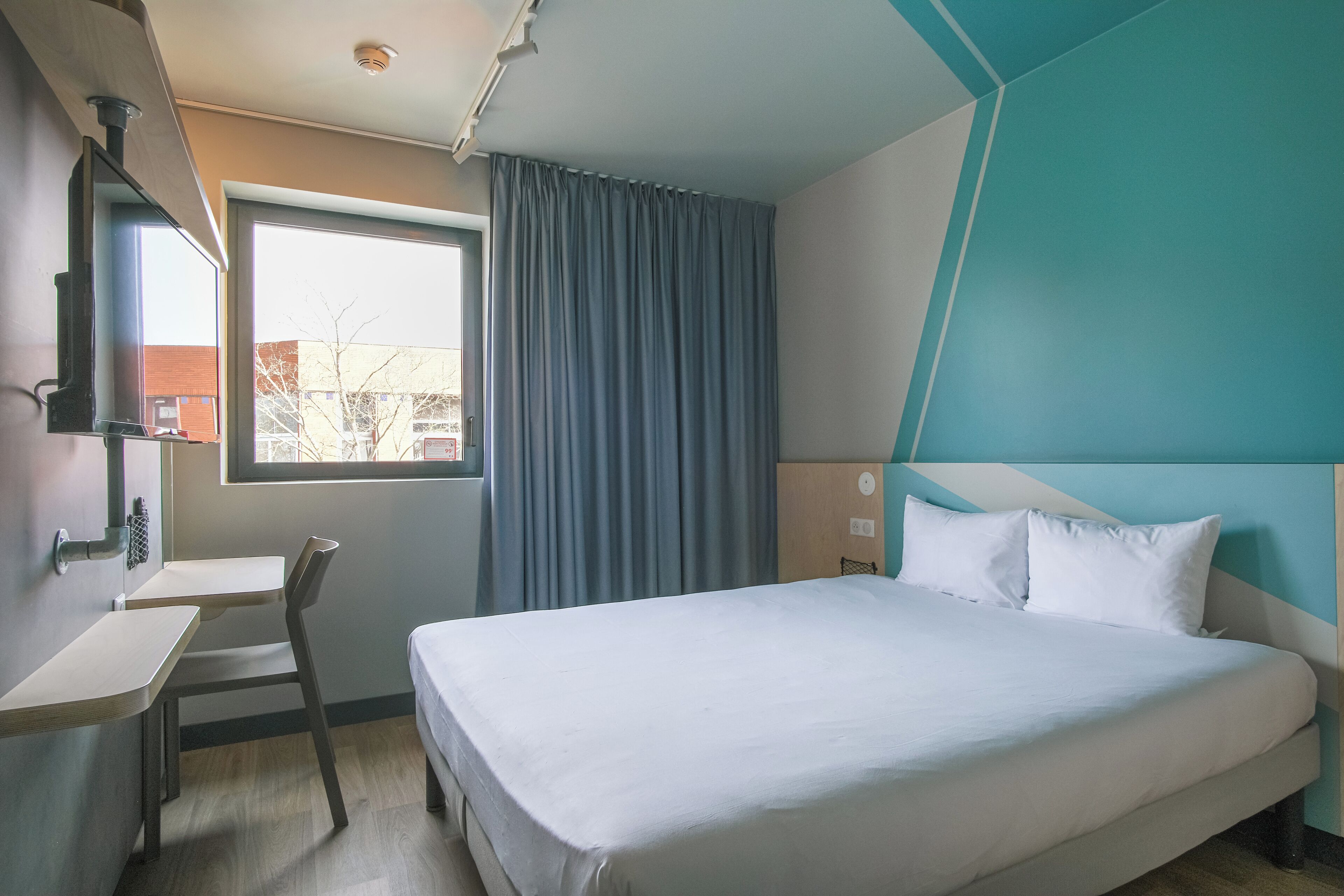 Ein Hotelzimmer mit Bett, Schreibtisch und Stuhl.