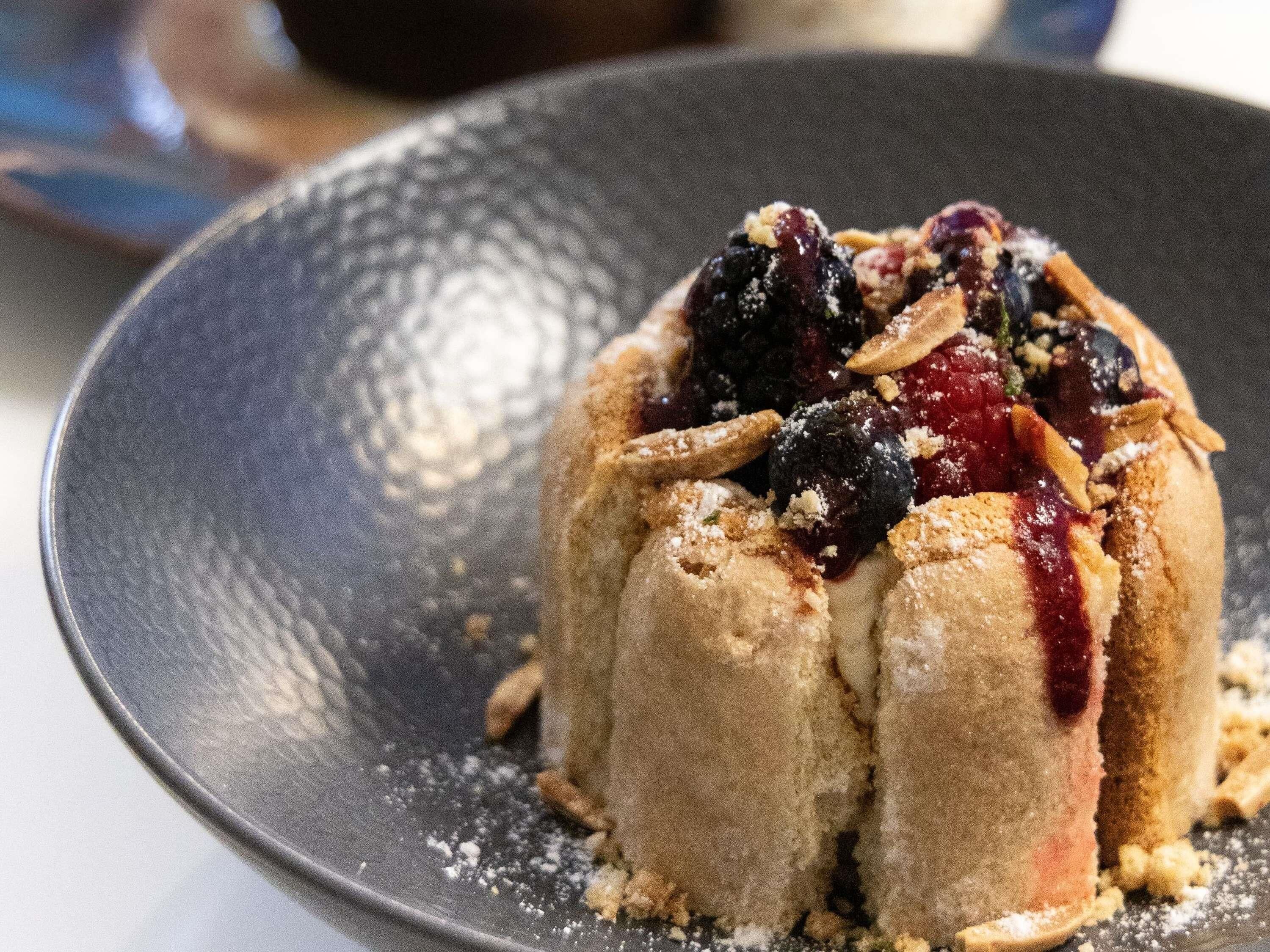 A dessert with berries and nuts on a plate.