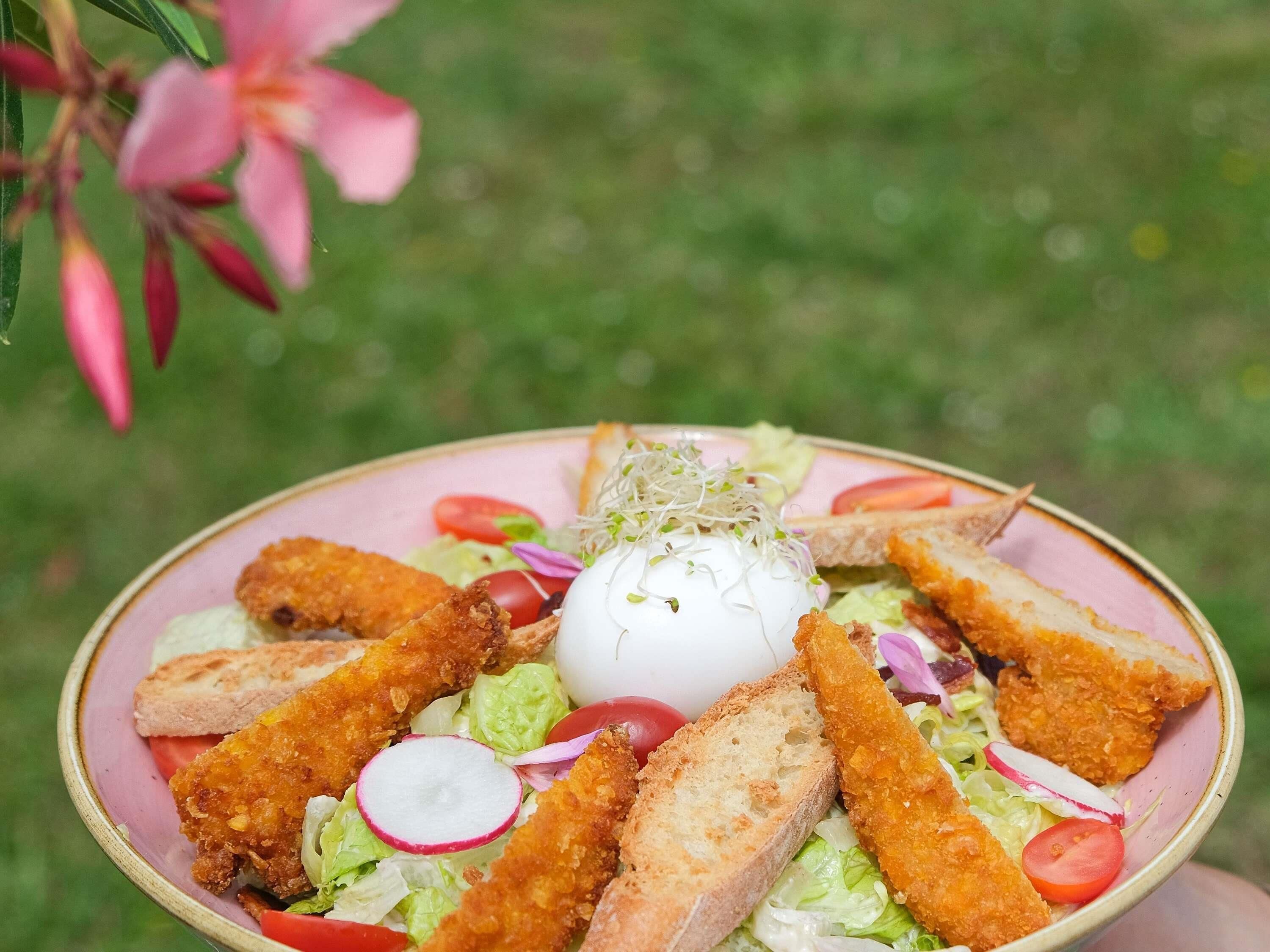 Une assiette composée de poulet pané, d’un œuf poché et d’une salade.