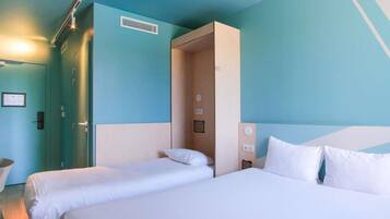 Une chambre d’hôtel avec deux lits, une porte et un luminaire.