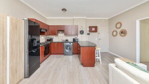 A modern kitchen with wooden cabinets, a built-in oven, and a washing machine. - Picturesque 2BD Apartment With Table Mountain View (Cape Town)