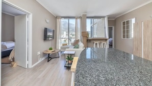 A modern apartment with a kitchen, living area, and a balcony with a mountain view. - Picturesque 2BD Apartment With Table Mountain View (Cape Town)