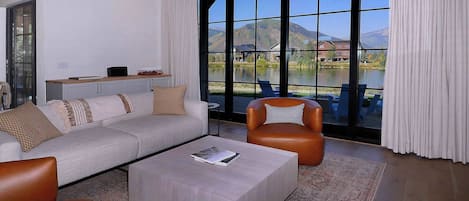 Una sala de estar moderna con un ventanal grande, un sofá, una mesa de centro y un sillón de cuero.