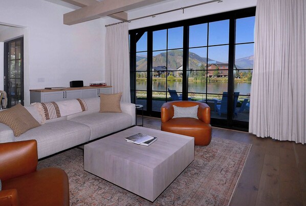 Una sala de estar moderna con un ventanal grande, un sofá, una mesa de centro y un sillón de cuero.