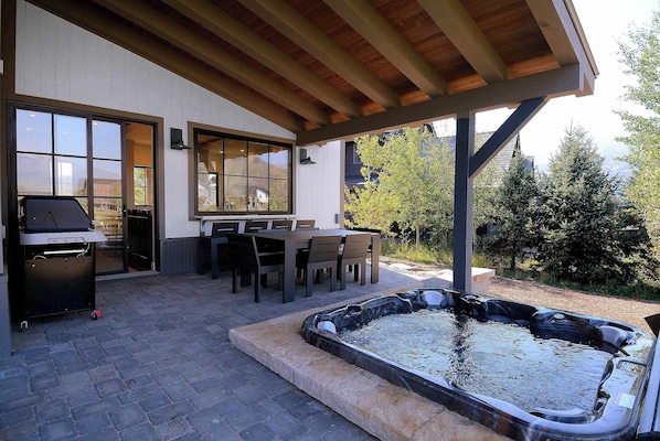 An outdoor patio with a barbecue grill, dining table, chairs, and a hot tub. - Lakeview Luxury, Hot tub, firepit, views! (Skyland & Surrounding Areas)