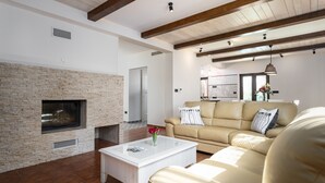 Una sala de estar con chimenea de piedra, un sofá color beige y una mesa de centro blanca.