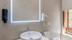 A bathroom with a large mirror, a sink, a towel rack, and a hairdryer mounted on the wall. - Recaredo, Nº4-1 bedroom apartment 2nd floor (Sevilla)