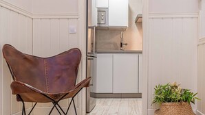 A chair with a unique design, a kitchen area with white cabinets, and a woven basket with plants. - Recaredo, Nº4-1 bedroom apartment 2nd floor (Sevilla)