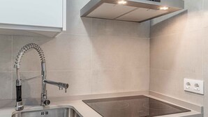 A modern kitchen with a stainless steel sink, a built-in stovetop, and a Bosch range hood. - Recaredo, Nº4-1 bedroom apartment 2nd floor (Sevilla)