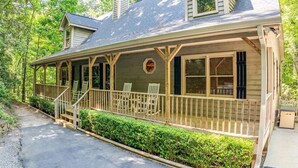 A wooden cabin with a porch, steps, and two chairs. - Rustic Elegance-Luxury Home Loaded with Amenities (Helen)