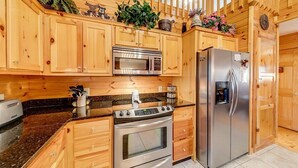 A kitchen with wooden cabinets, a microwave, a stove, and a refrigerator. - Rustic Elegance-Luxury Home Loaded with Amenities (Helen)