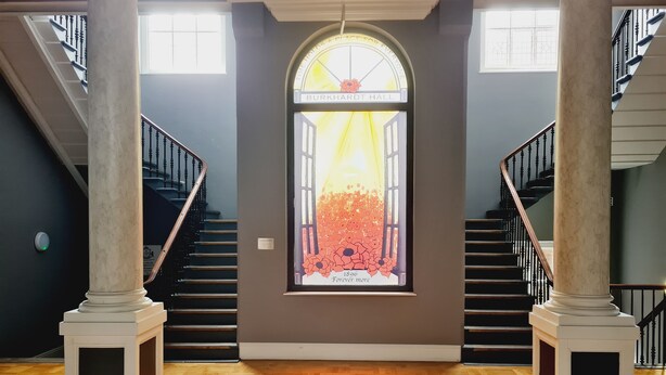Un magnifique escalier orné de colonnes en marbre, une grande fenêtre à vitraux et un plancher en parquet.