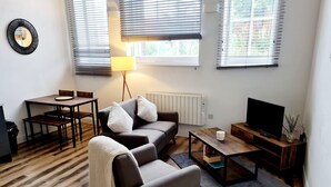 Un salon moderne comprenant un canapé, un fauteuil, une table basse, un téléviseur et un coin repas.