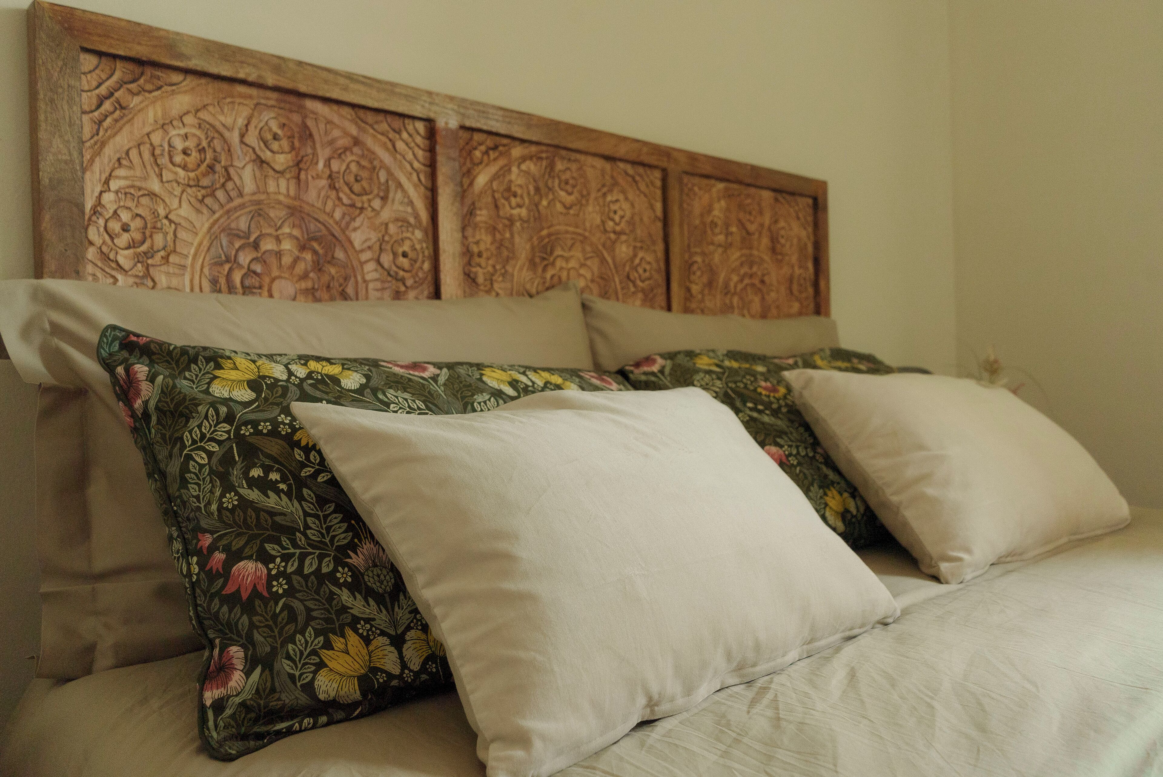 A bed with floral-patterned pillows and a wooden headboard.