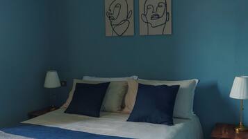 A bedroom with a bed, two wall art pieces, a nightstand, and a lamp.