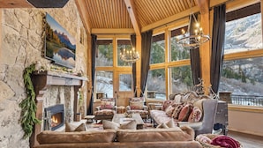 A cozy interior with a fireplace, plush seating, and large windows offering scenic views. - Snowfall Castle, Unbelievable Views, Rustic Mountain Masterpiece (Sundance)