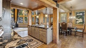 A spacious kitchen with wooden beams, a marble countertop, and a dining area with a chandelier. - Snowfall Castle, Unbelievable Views, Rustic Mountain Masterpiece (Sundance)