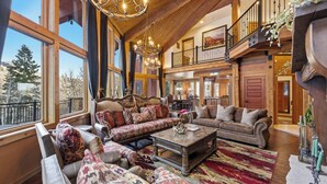 A spacious living room with large windows, a high ceiling, and a cozy fireplace. - Snowfall Castle, Unbelievable Views, Rustic Mountain Masterpiece (Sundance)