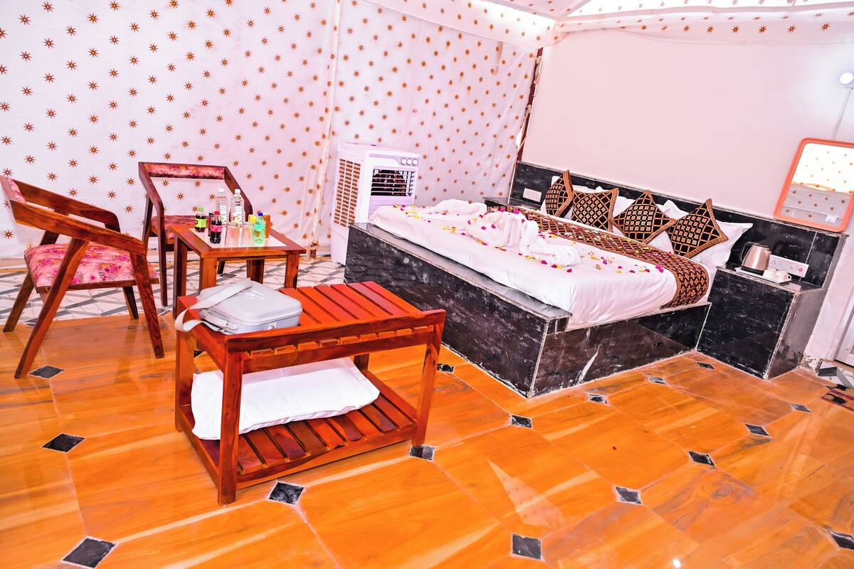 Ein Zimmer mit einem Bett, einem Holztisch mit Stühlen, einem kleinen Tisch mit Flaschen und einer Wand-Klimaanlage.