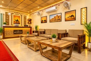 A reception area with a reception desk, sofas, and coffee tables. -  Barkha Desert Safari Camp Sam Sand Dunes (Jaisalmer)