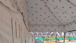 A corridor with a tiled floor and a green carpeted area, leading to a covered outdoor space with a patterned ceiling. -  Barkha Desert Safari Camp Sam Sand Dunes (Jaisalmer)