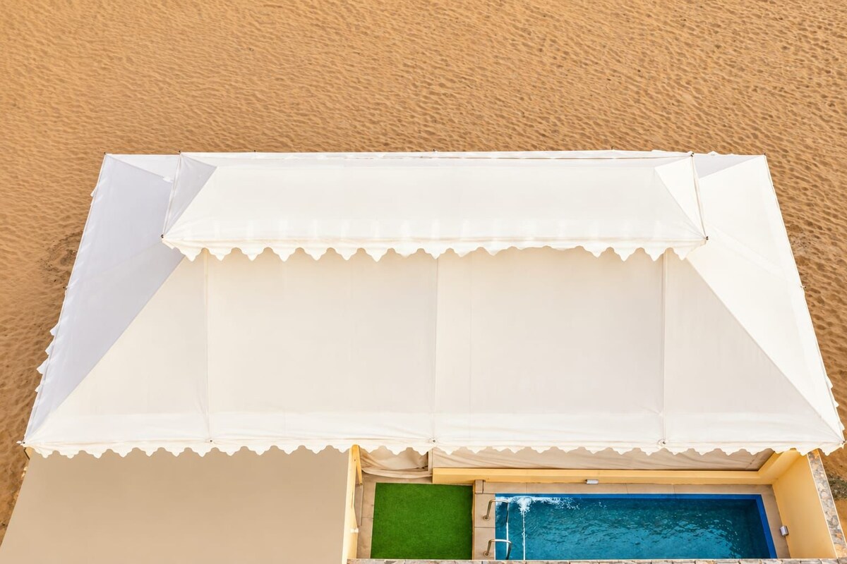 A beachside pool area with a white canopy and a small pool.
