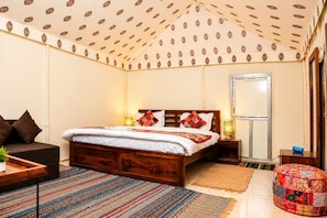 Une chambre à coucher comprenant un lit, des tables de chevet, une commode, un canapé, un tapis coloré et un plafond à motifs.