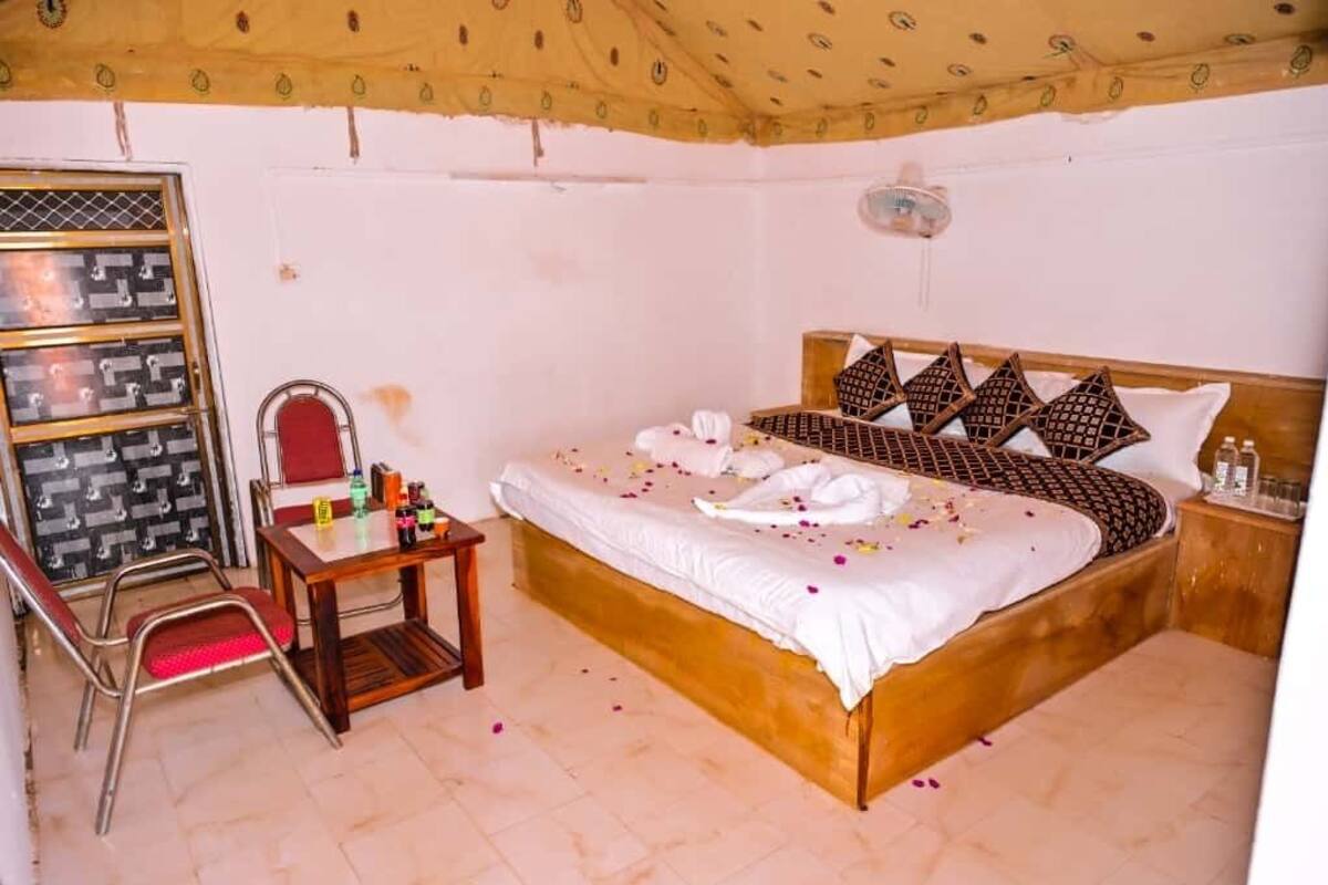 Ein Schlafzimmer mit einem Bett, einem kleinen Tisch mit Toilettenartikeln, einem Sessel und einem Kleiderschrank.