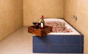 A bathtub with rose petals, a wooden tray with wine glasses and a bottle, and a showerhead. -  Barkha Desert Safari Camp Sam Sand Dunes (Jaisalmer)
