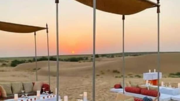 A desert camp with a canopy bed, white tables with candles, and lanterns. -  Barkha Desert Safari Camp Sam Sand Dunes (Jaisalmer)