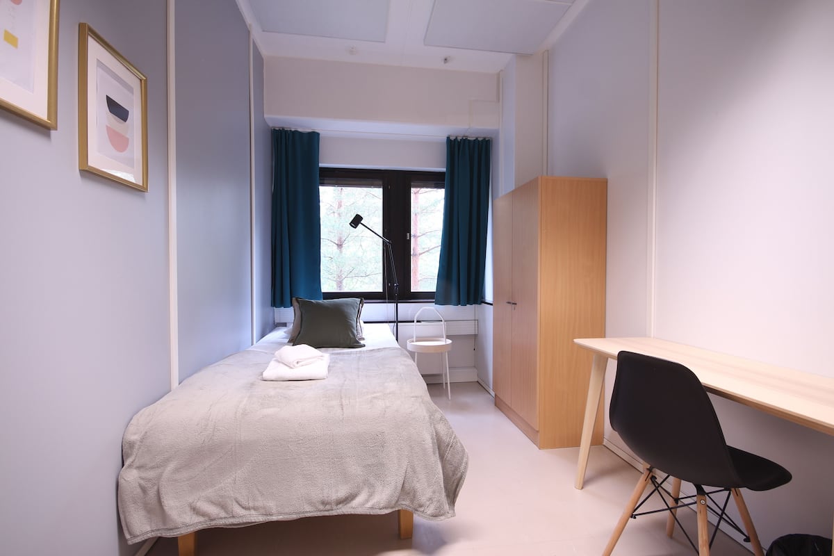 A bedroom with a bed, a desk, and a wardrobe.