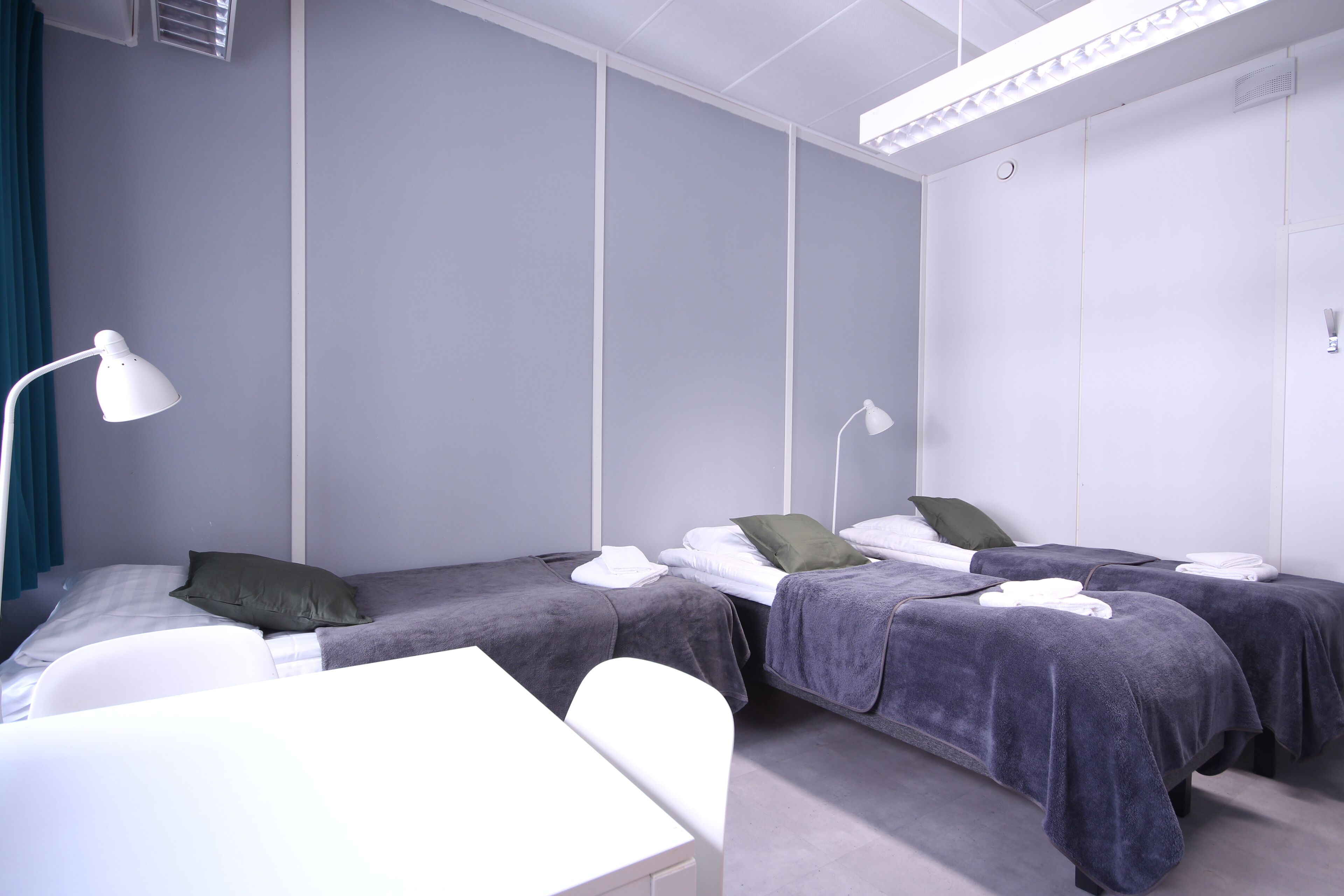 A hotel room with two beds, a desk, and a chair.