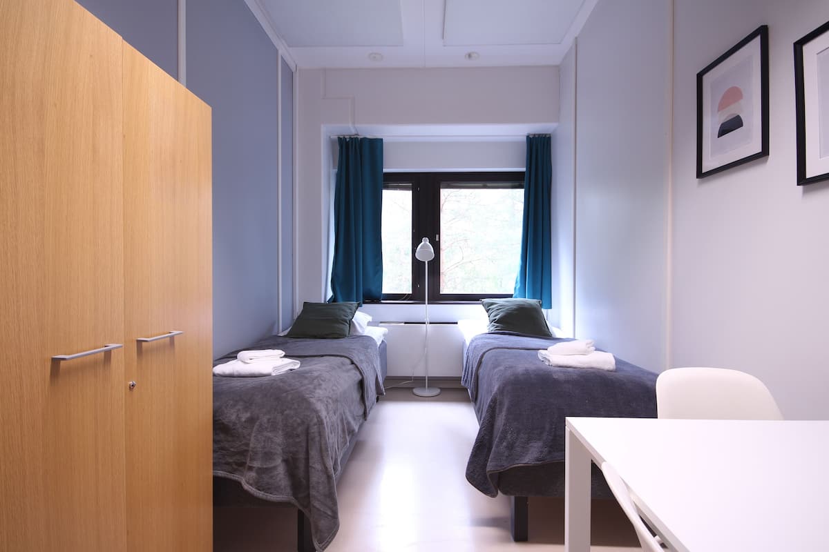 A room with two beds, a desk, and a wardrobe.