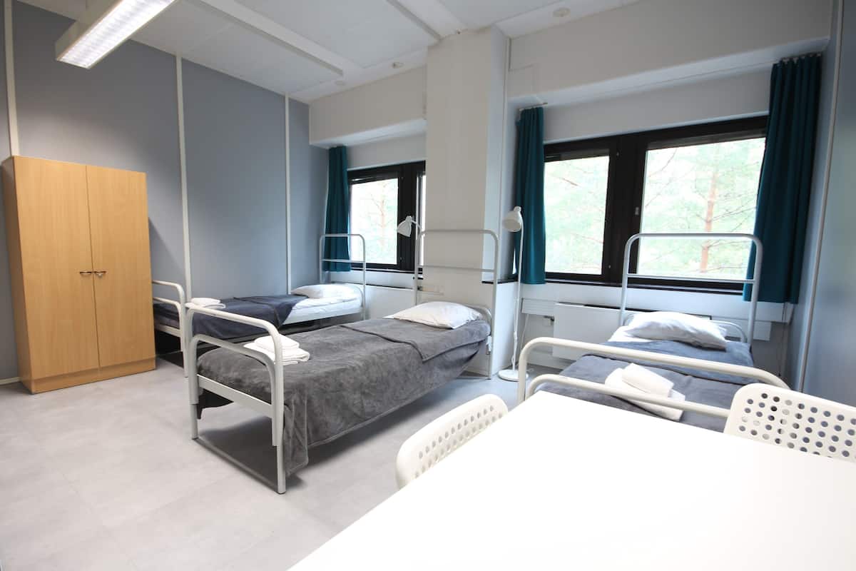 A hospital room with two beds, a desk, and a wardrobe.