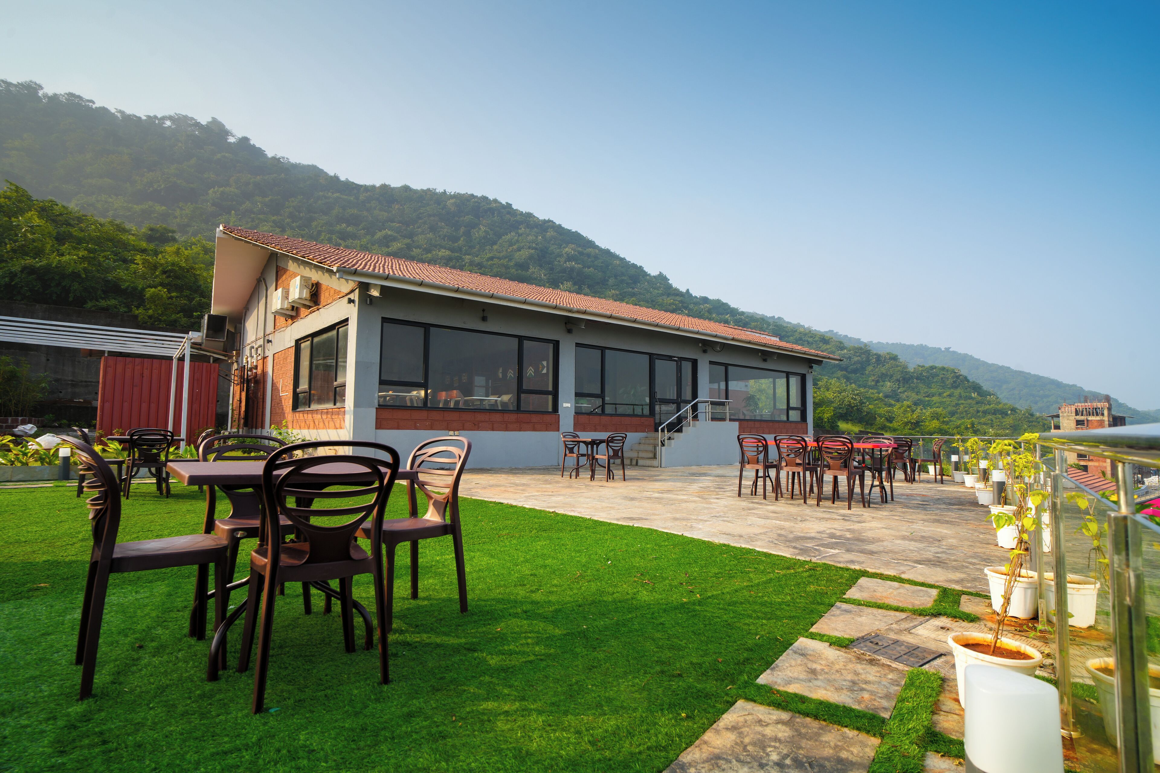 Un ristorante con posti a sedere all'aperto, una terrazza e vista su una collina boscosa.