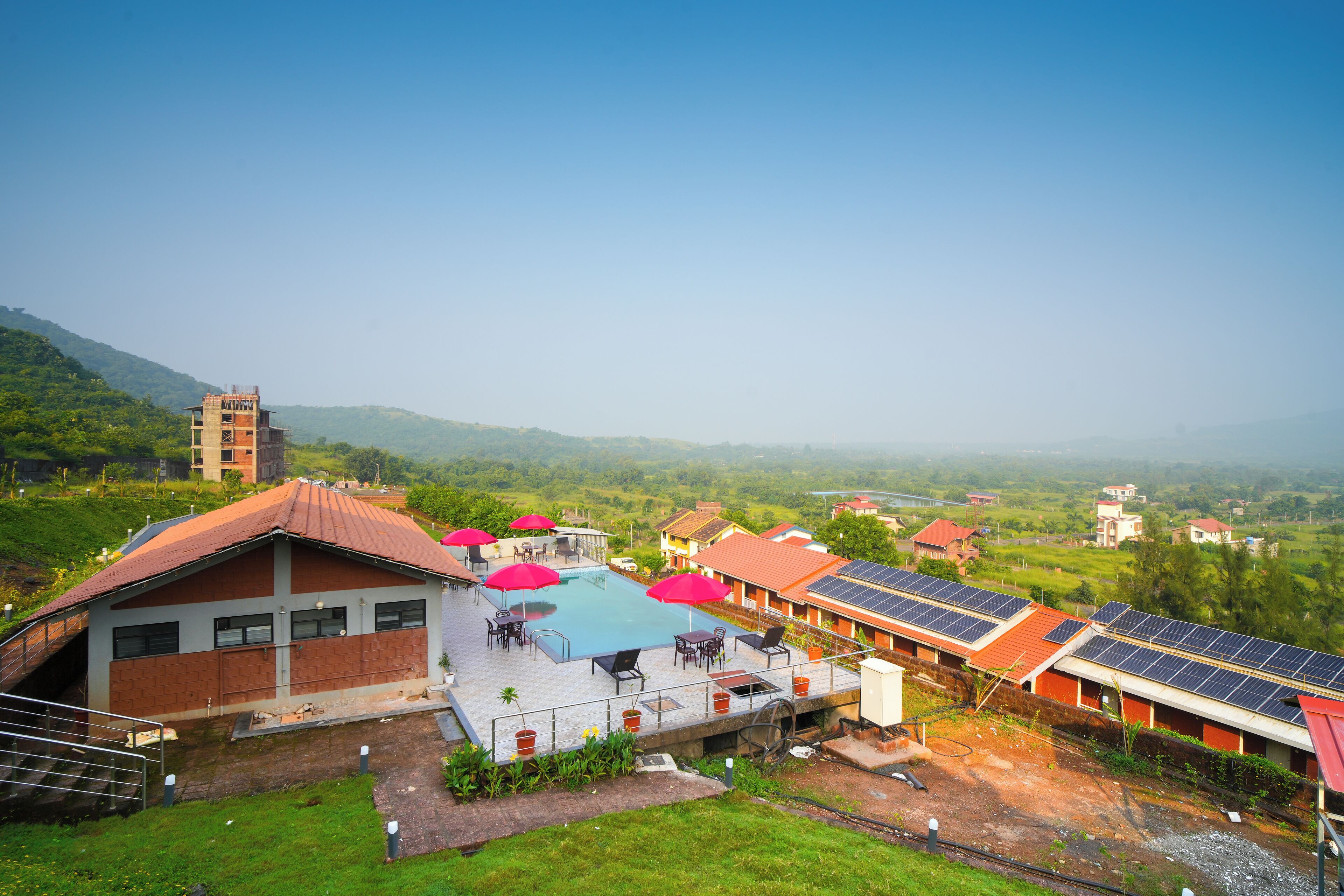 A hotel with a swimming pool, solar panels, and a view of the surrounding landscape.