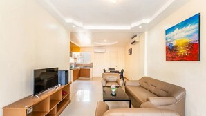 A modern living room with a flat-screen TV, a sofa, a coffee table, and a painting on the wall. - WOW! 3BR House w/Karaoke ,Swimming Pool, Pet Friendly (Lapu-Lapu City)