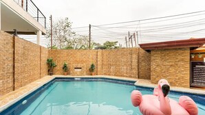 A swimming pool with a pink inflatable flamingo float, surrounded by brick walls and potted plants. - WOW! 3BR House w/Karaoke ,Swimming Pool, Pet Friendly (Lapu-Lapu City)